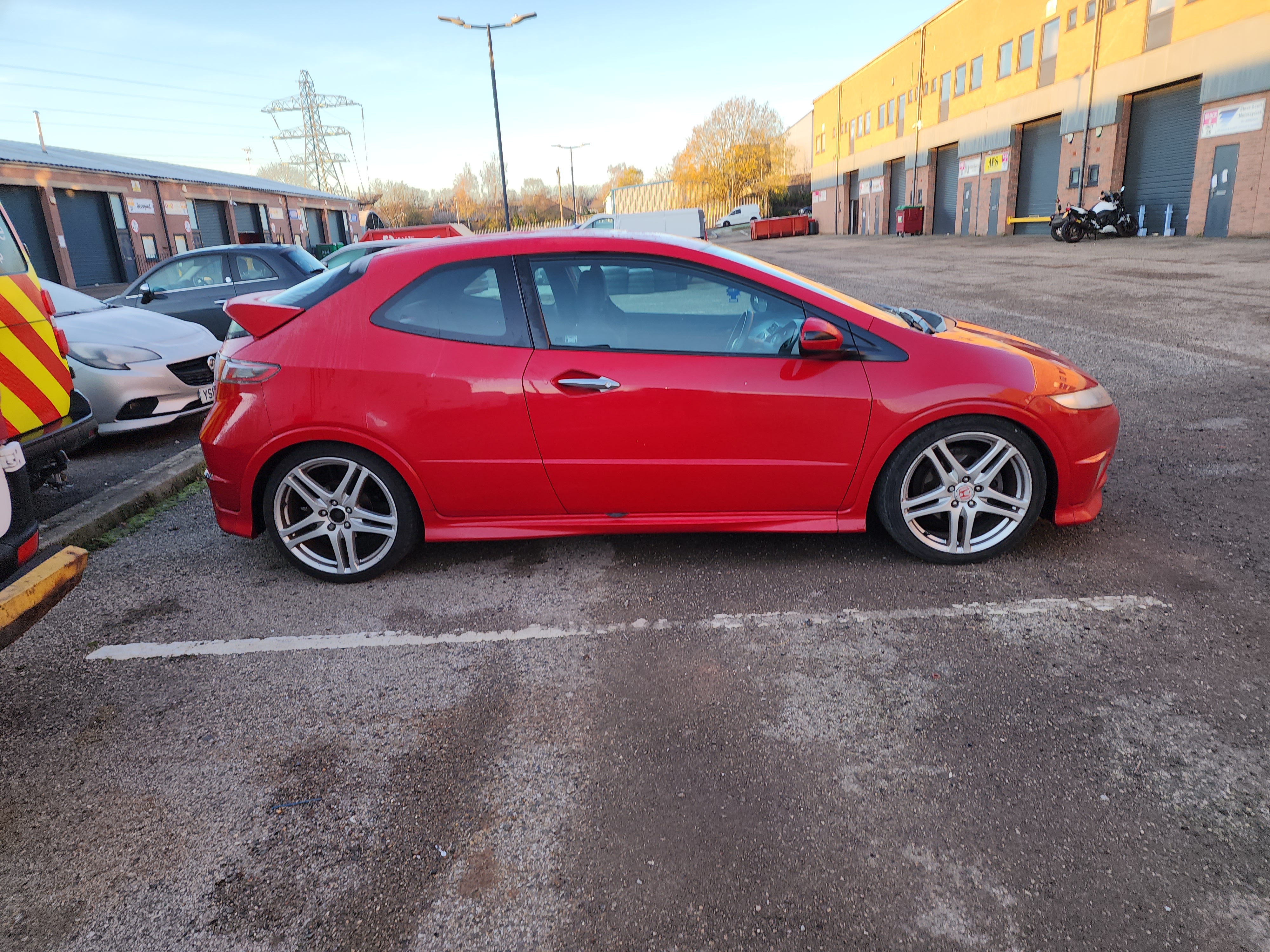 Right-side view of the red Honda Civic Type R FN2 parked outside a workshop